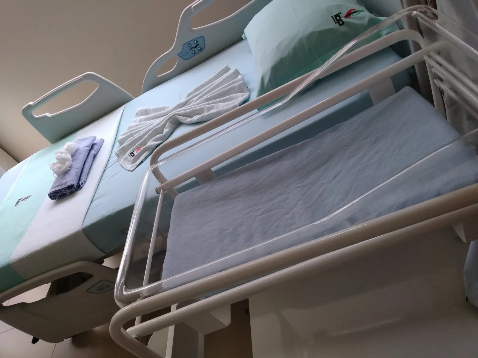 Berço de recém-nascido arrumado por Thalles Diamantino ao lado do leito, num quarto de hospital